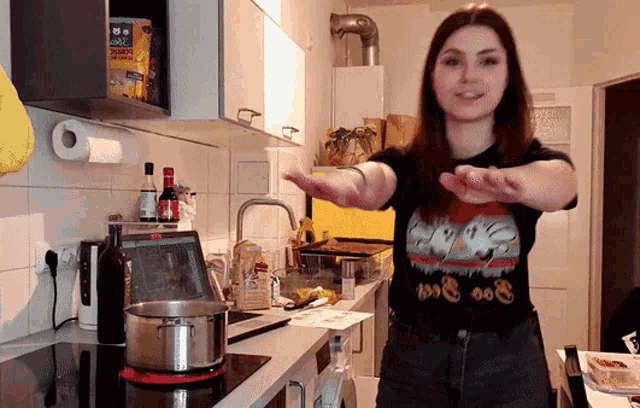 a woman in a kitchen wearing a t-shirt that says ' boo ' on it