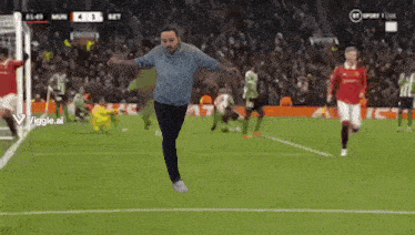 a man is jumping in the air on a soccer field in front of a crowd .