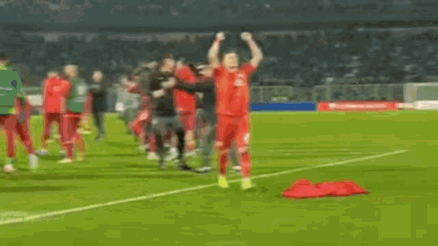 a soccer player is standing on the field with his hands in the air .