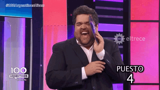a man in a suit is holding a piece of paper in front of a sign that says puesto