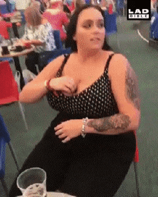 a woman with a tattoo on her arm is sitting at a table with a glass of beer in front of her