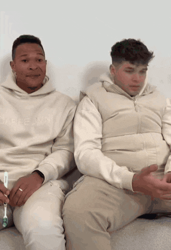 two men sitting next to each other with one wearing a hoodie that says ' able mini ' on it