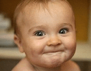 a baby is making a funny face and smiling .