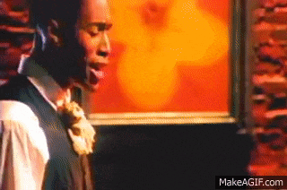 a man in a suit and tie is standing in front of a wall with a picture on it .