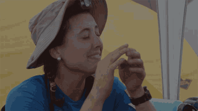 a woman wearing a blue shirt and a hat with a light on her head is smiling