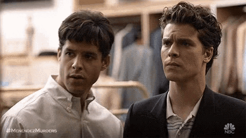 two men are standing next to each other in a clothing store .