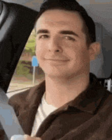 a man is sitting in the back seat of a car and smiling .