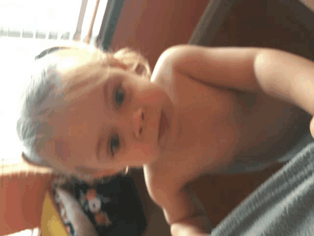 a little girl without a shirt is laying on a blanket