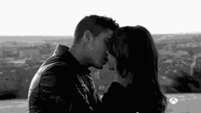 a black and white photo of a man and a woman kissing .