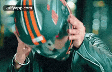 a person is putting on a motorcycle helmet and covering their face with it .