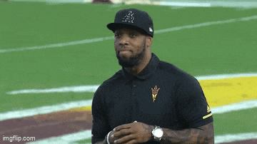 a man wearing a hat with the letter a on it stands on a football field ..