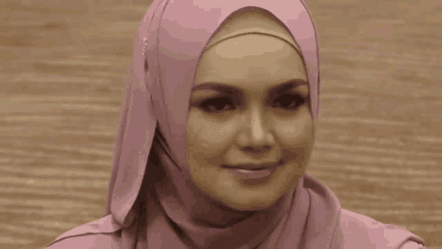 a woman wearing a pink hijab is smiling