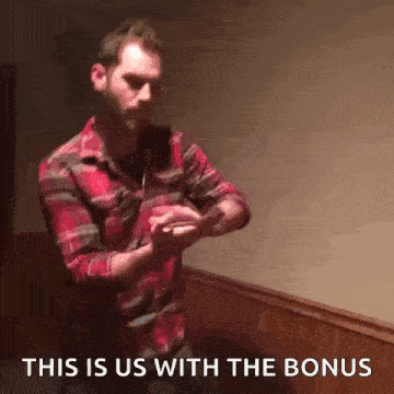 a man in a plaid shirt is standing in front of a wooden wall with the words this is us with the bonus above him .