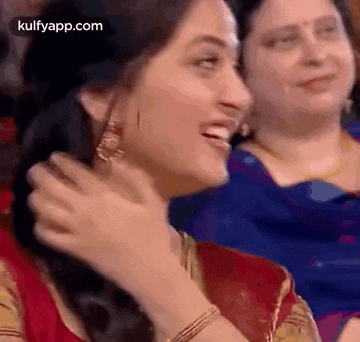 a woman is smiling and laughing while sitting in a crowd .