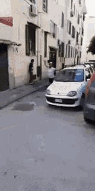 a white car is parked on the side of a city street .