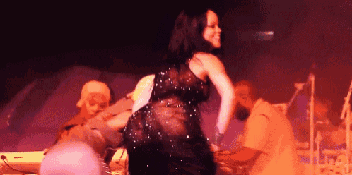 a woman in a black dress is dancing on a stage in front of a keyboard .