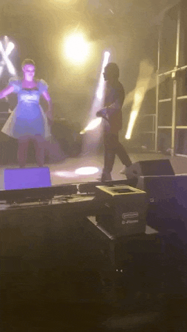 a woman in a blue dress is dancing on a stage with a man in a red jacket .
