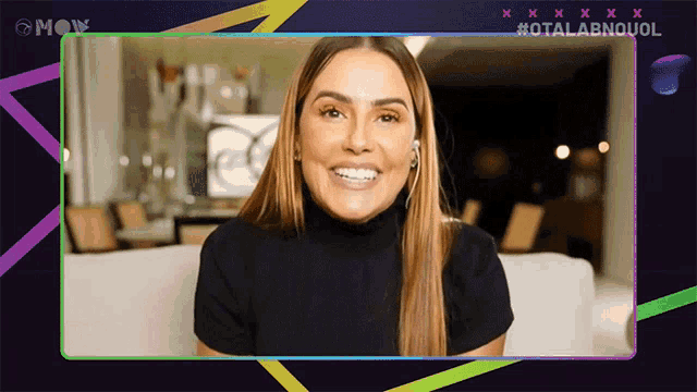 a woman in a black turtleneck is smiling in front of a screen that says moy
