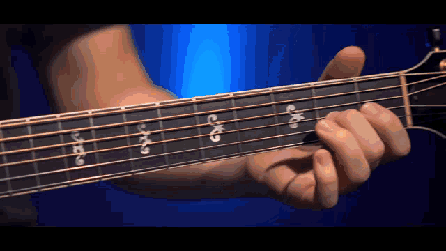 a close up of a person playing a guitar with a blue background