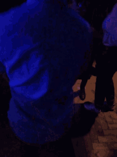 a man in a grey shirt is kneeling down in front of a blue light
