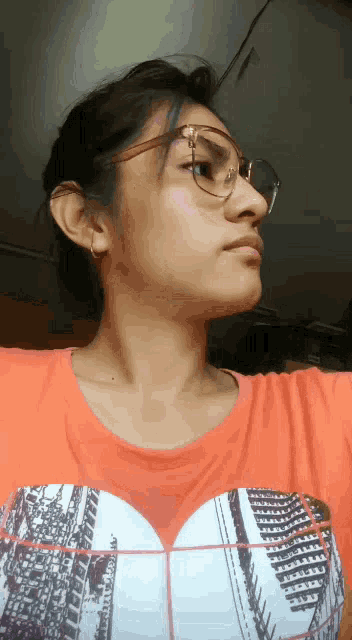a girl wearing glasses and an orange shirt has a heart on her chest
