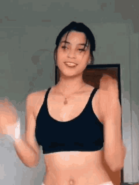 the woman is wearing a black sports bra and white shorts and is dancing .