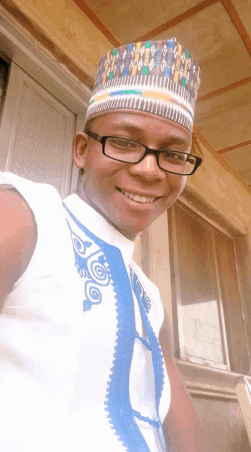 a man wearing glasses and a hat smiles for a picture
