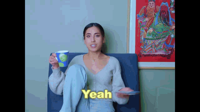 a woman is sitting in a chair with her legs crossed and holding a cup of coffee and saying yeah