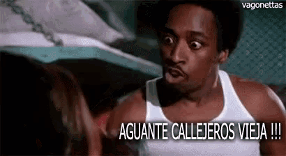 a man in a white tank top is talking to a woman and the words aguante callejeros vieja are above him .