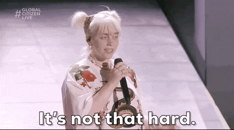 billie eilish is singing into a microphone on a stage and saying `` it 's not that hard . ''