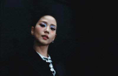 a close up of a woman 's face wearing a tuxedo and tie