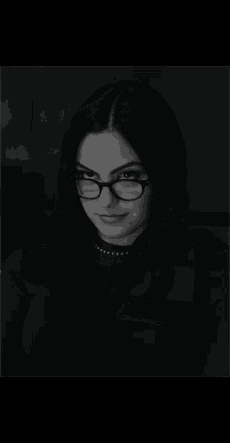 a black and white photo of a woman wearing glasses and a black shirt
