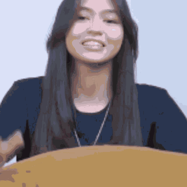 a woman in a blue shirt is smiling and looking at the camera