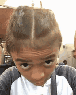 a young boy with braids on his head is making a funny face