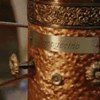 a close up of a copper coffee maker with a label that says cappuccino