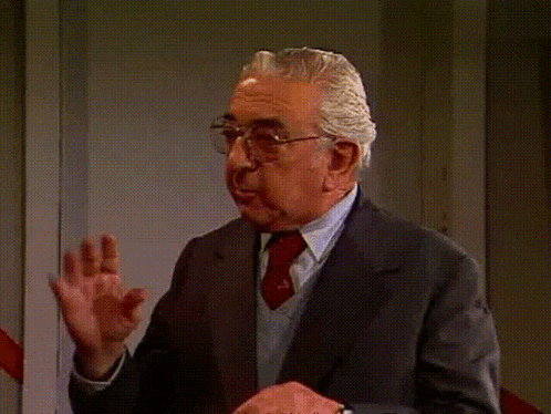 a man in a suit and tie is talking and pointing