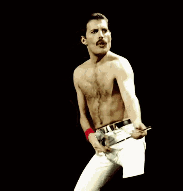 a shirtless man with a mustache holds a microphone in his hand