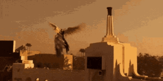 a statue of a man with wings is flying over a building .