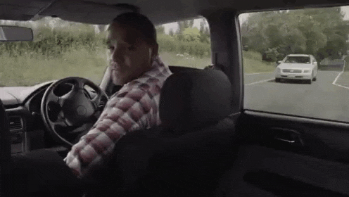 a man is sitting in the driver 's seat of a car .
