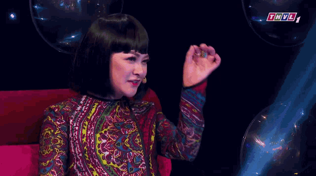 a woman in a colorful dress is sitting in front of a microphone with the letters thvl on the bottom right