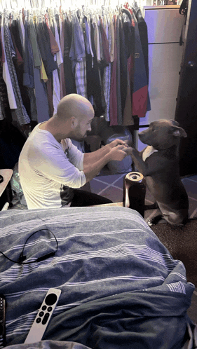 a man and a dog are sitting on a bed and the dog is wearing a shirt with the letter b on it