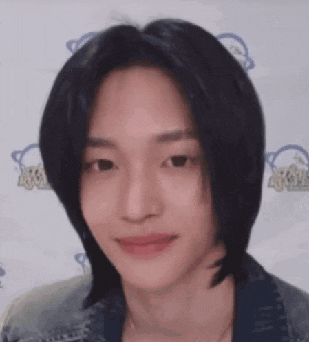 a close up of a young man 's face with long black hair .