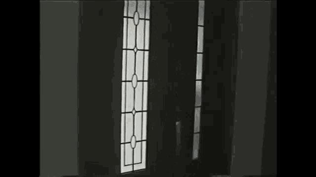 two men are standing in a doorway in a dark room .