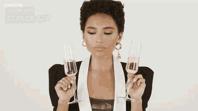a woman in a suit is holding two glasses of champagne in her hands