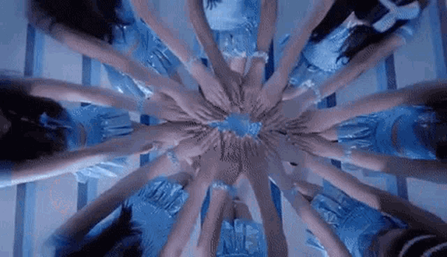 a group of women are standing in a circle with their hands in the middle .