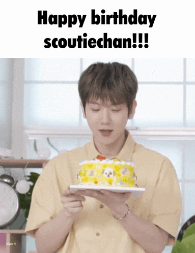 a man in a yellow shirt is holding a birthday cake in his hands