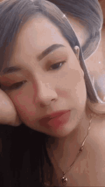 a close up of a woman 's face with her hand on her face .