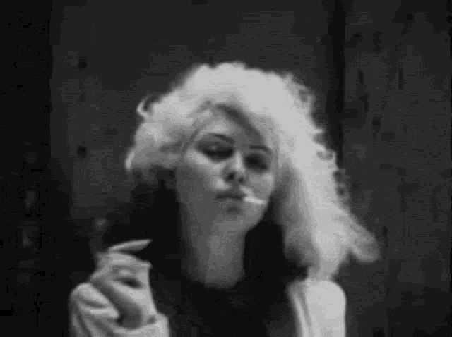 a woman with white hair is smoking a cigarette .
