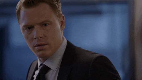 a man in a suit and tie looks to the side