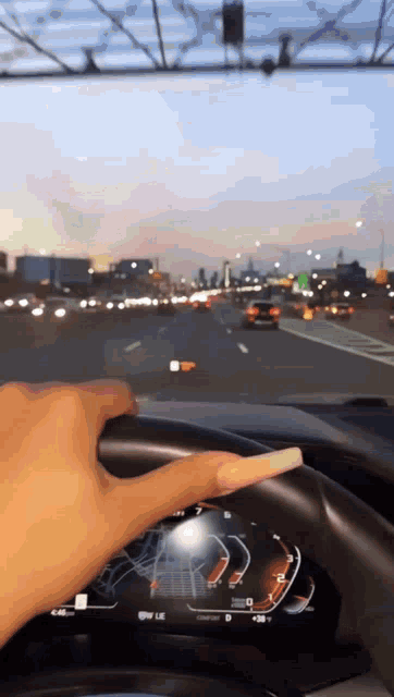 a woman with long nails is driving a car on a highway .
